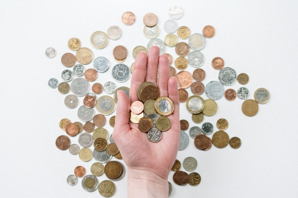 A hand holding coins from many countries